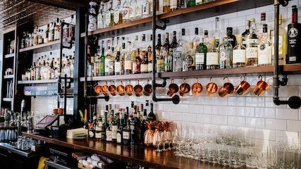 Picture of a bar with several rows of shelves with liquor bottles