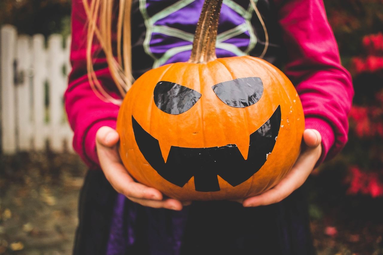 Jack-o-lantern in a young child's dressed as a witch.
