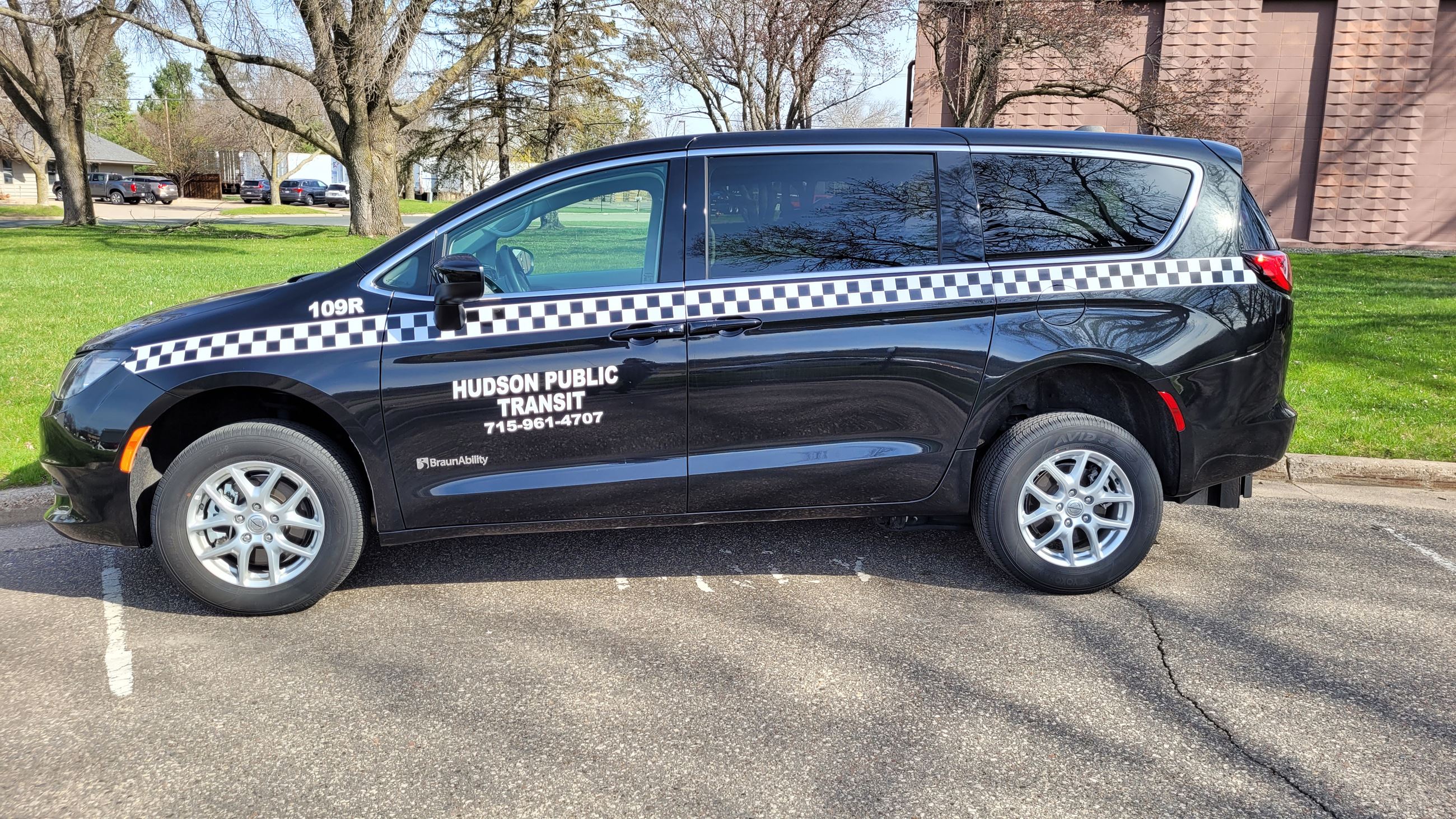 Minivan parked in front of an office building. The van has a public transit sticker on the door. 