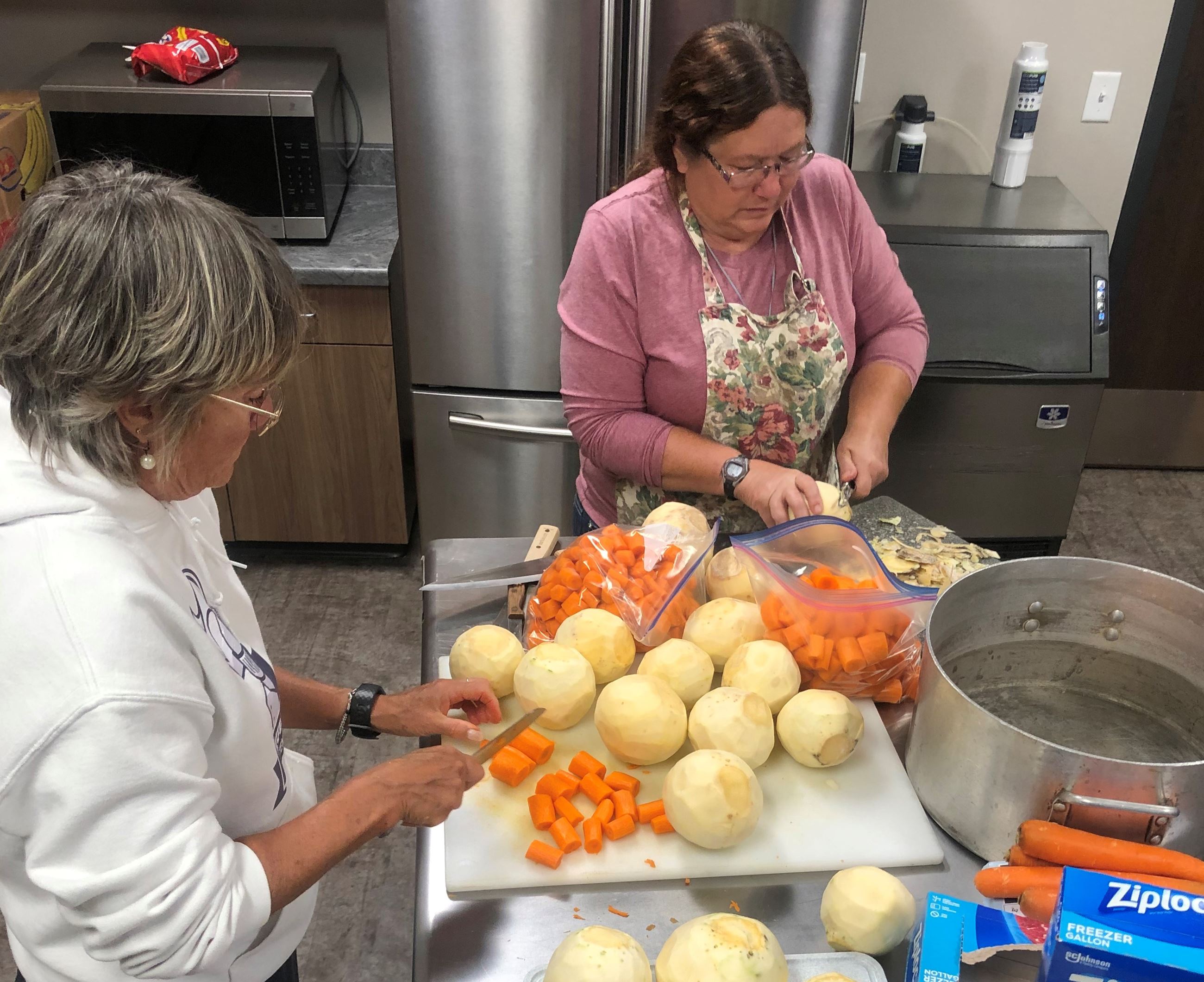 Kitchen prep work with two women cutting vegetables. 
